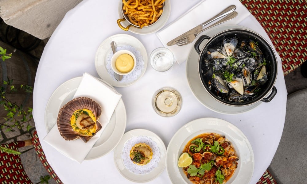 Fete de la moule på Luzette - ett uppdukat bord med olika musselrätter, vin och pommes